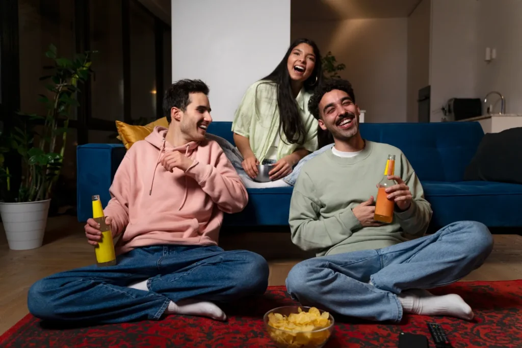 Prueba IPTV gratis para disfrutar con amigos en casa Tres amigos riendo en el salón mientras ven la televisión durante una prueba IPTV gratis